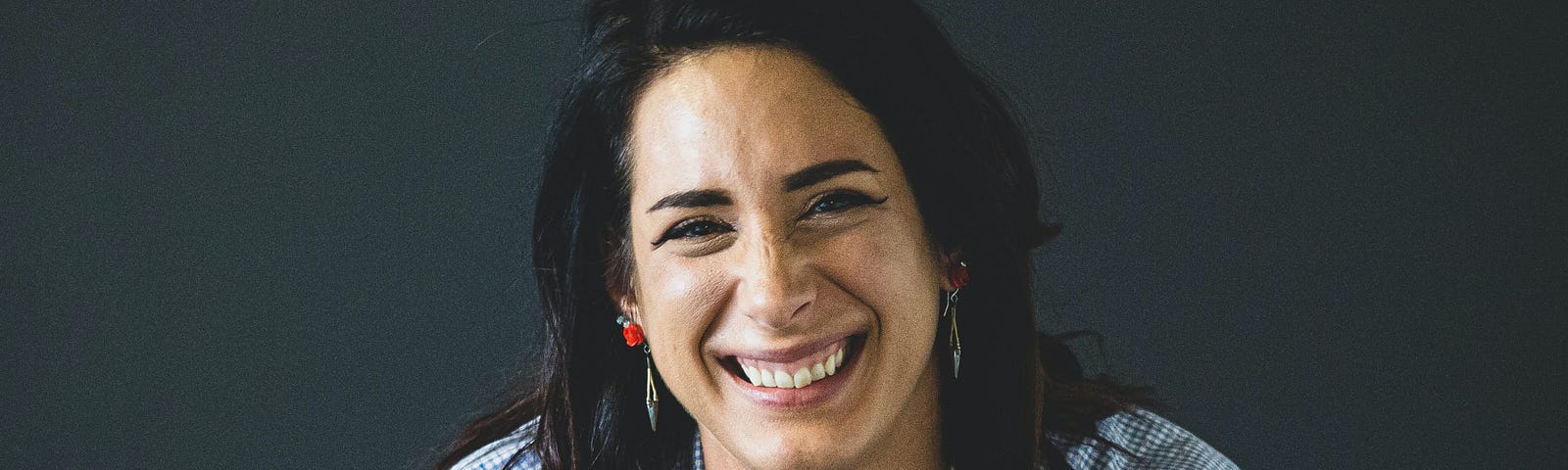 Dark haired brunette woman and possible mentor with long hair smiling right at the camera encouraging others to approach her with questions.