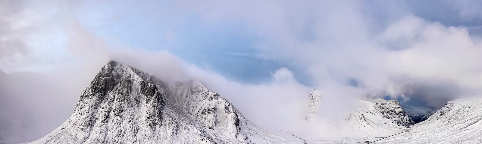 High mountain valley covered in snow with clouds brushing the mountaintops