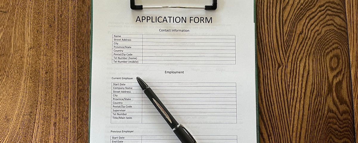 A generic application form on a clipboard accompanied by a pen