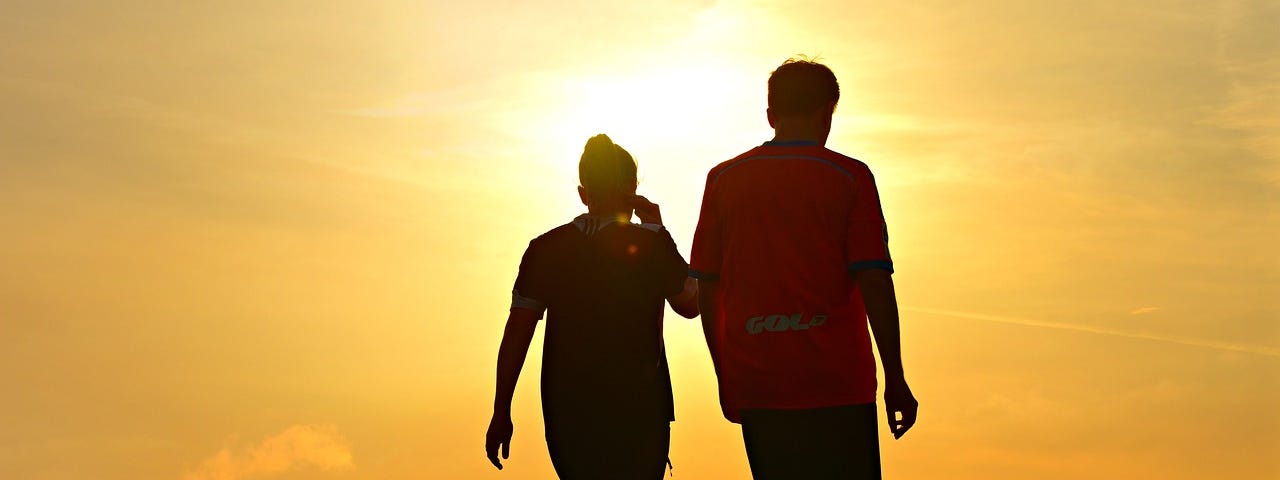 Two people walking at sunset