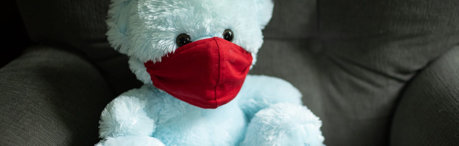 stuffed blue teddy bear wearing a red mask