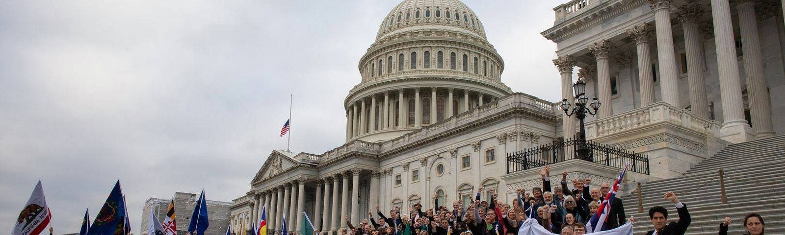 A group of people gather in front of the U.S. Capitol holding American Promise signs.