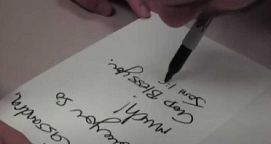 A person writing autograph with mouth