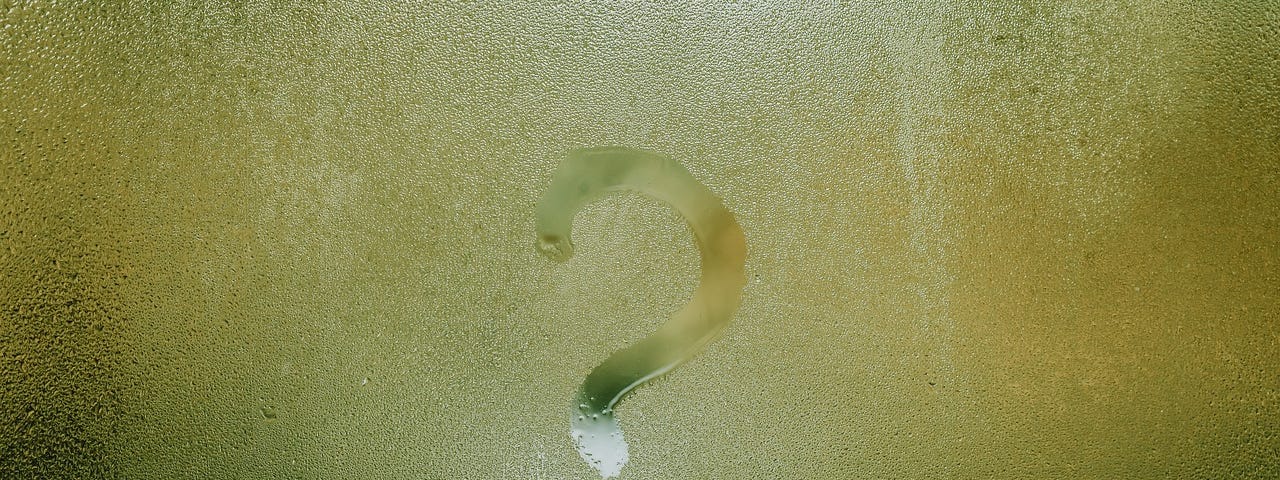 A question mark drawn on a wet window