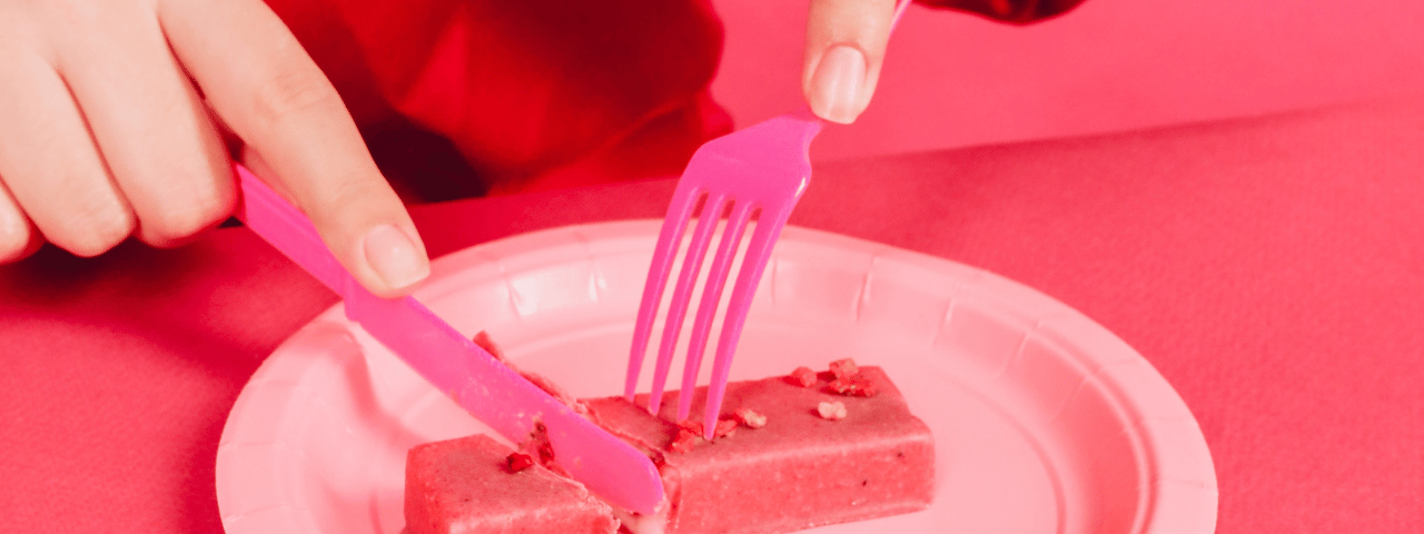 a pink photo with a woman eating a pink confection with a knife and fork.