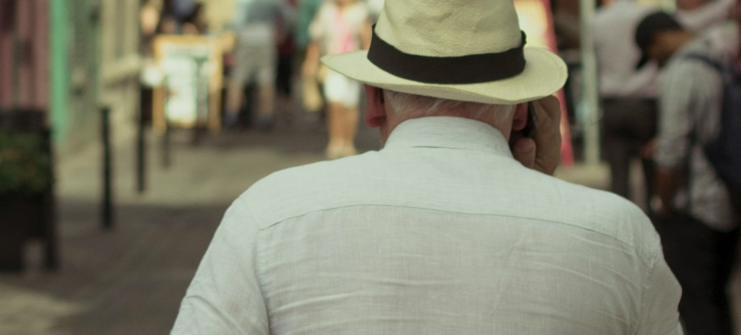 back of an elderly man wearing a hat, walking