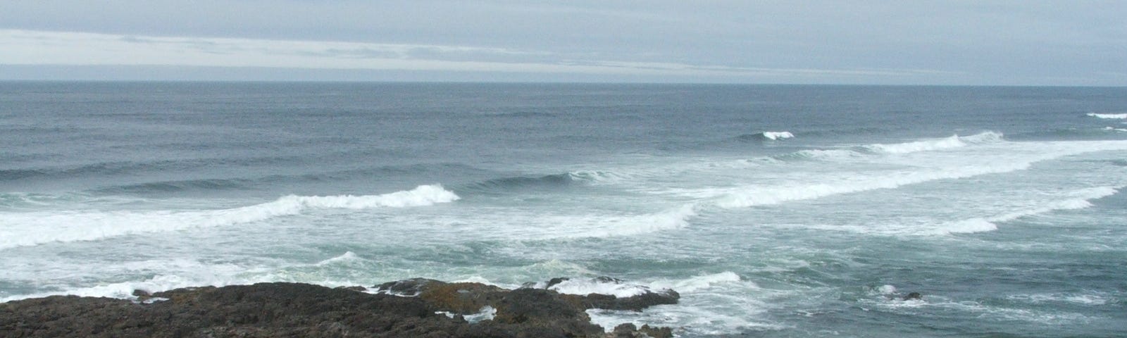 A picture of the beach on a cloudy day, with waves crashing in