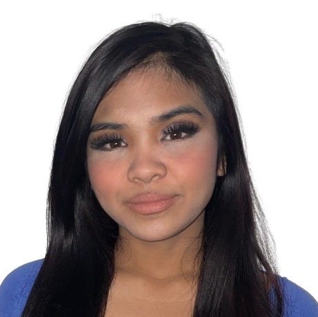 Photo of Janice, a Filipino woman, from the chest up. Her long, straight black hair drapes over a light cobalt blue cardigan. She is facing the camera with long lashes over dark brown eyes, rosy blush, and pink lipstick over a light smile.