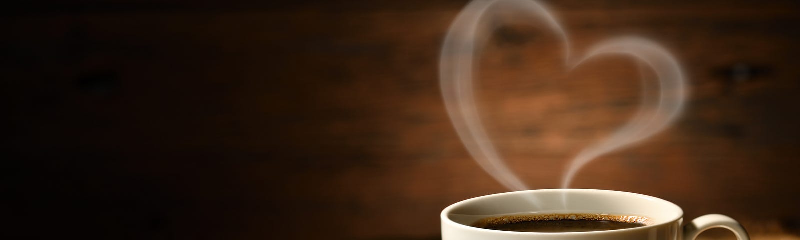 A white cup of coffee (with beans on the side) emits a heart-shaped smoke ring. Coffee reduces the risk of some cancers.