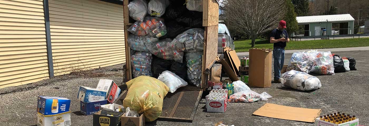 Large pickup truck w/ covered homemade trailer stocked fully with bags of recycled bottles. Dozens of more bags on the ground