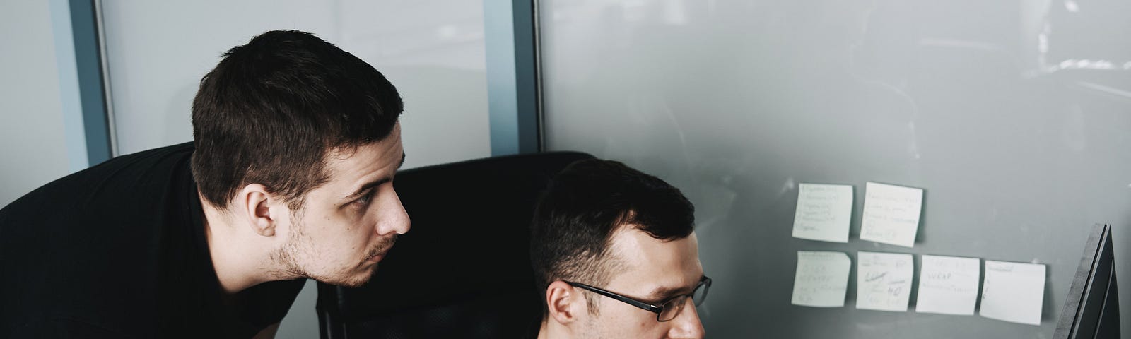 2 men working full steam in front of their laptops.