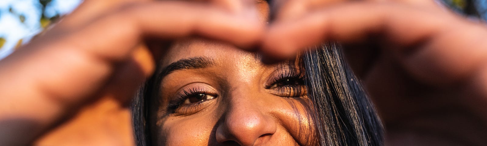 Indian woman making heart sign, and smiling through it.