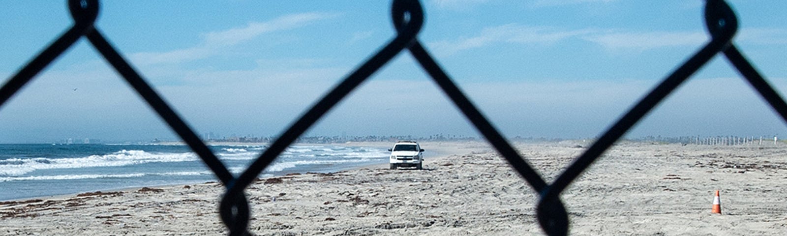 The United States seen through fencing at the border of the U.S. and Tijuana, Mexico. A Border Patrol vehicle can be seen through the chain-link fence. Photo by Robert Stribley.