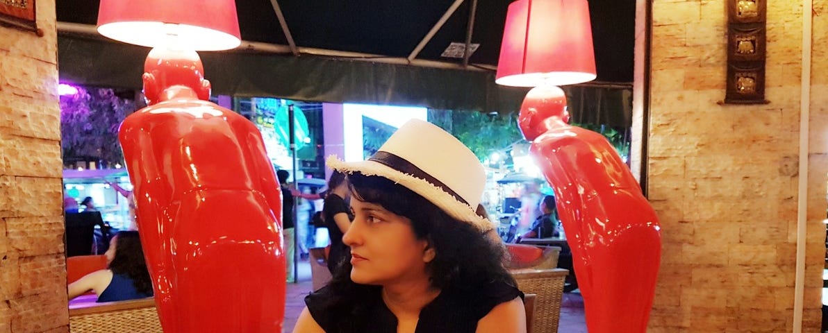 Image of a women with a hat sitting in a resturant looking to her side.
