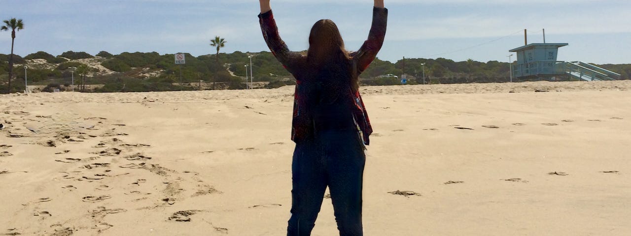 A girl on the beach with her arms up to reach the sun and an airplane between her hands.