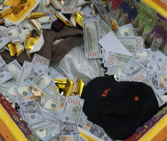 Gold coffin, filled with 100-dollar bills, a hat, and other items. This is a funeral in Cambodia.