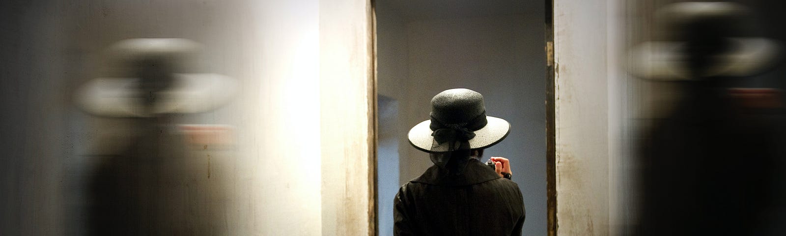 A woman in a hat walks out or in a door.