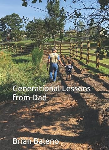 A father holds a young son’s hand walking on a dirt path on a farm within wood fencing and greenery