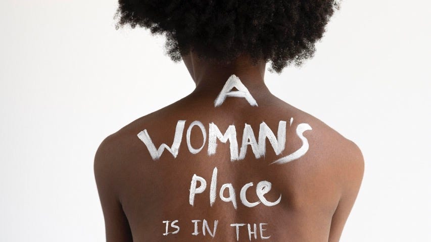 close up on a woman’s back with the words “a woman’s place is in the revolution”