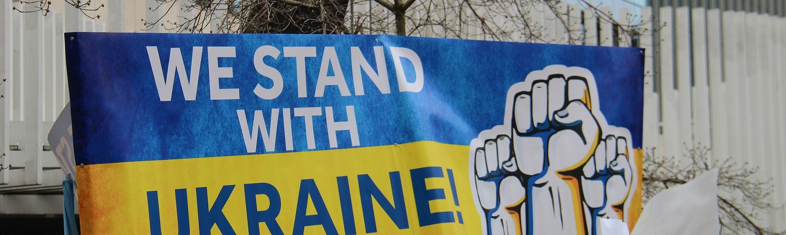 Protestors holding a banner that says “We stand with Ukraine.”