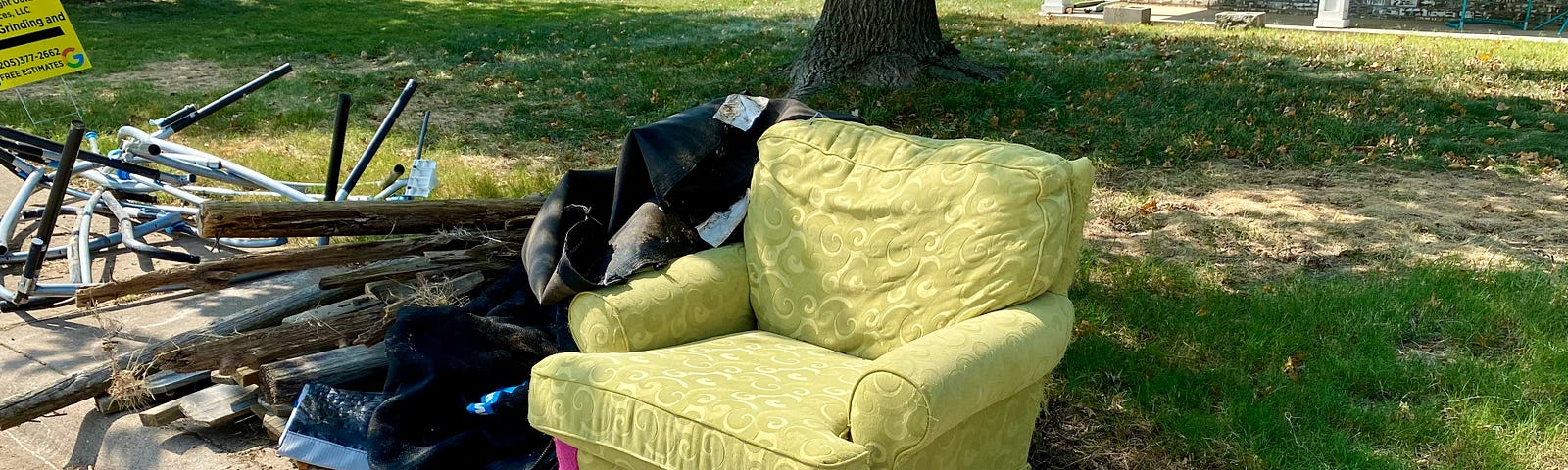 green chair sitting by the curb with junk