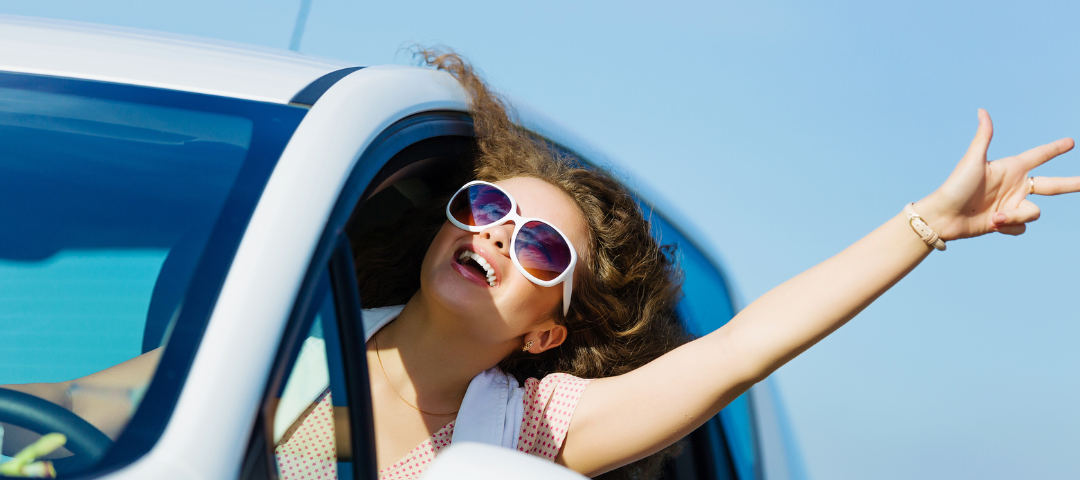 Woman driving car with her hand out the window.