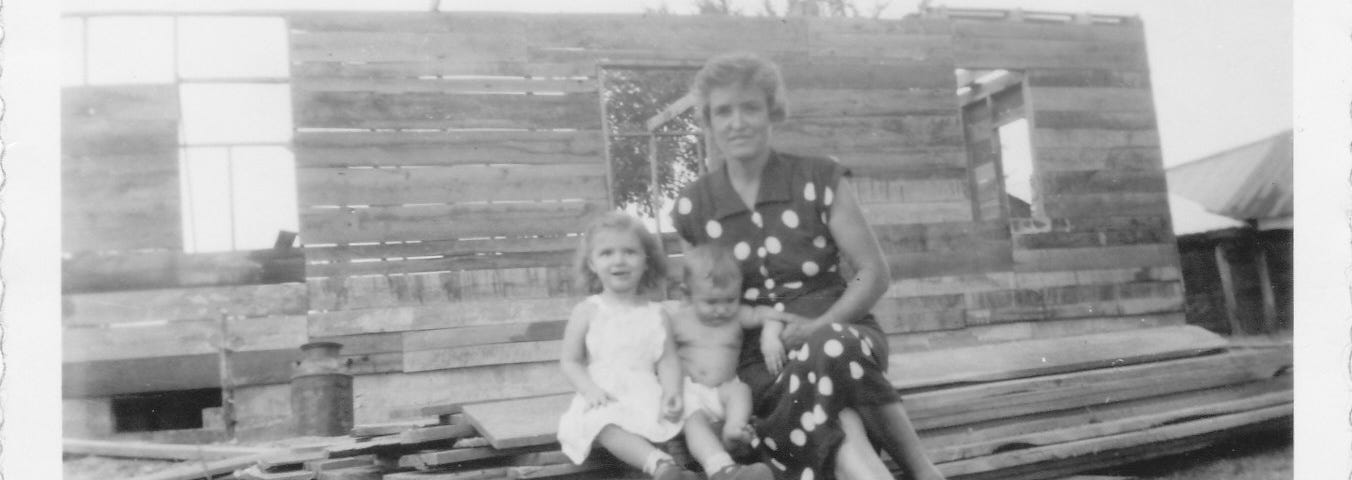 Grandma with grandkids, sitting on building materials for her farmhouse.