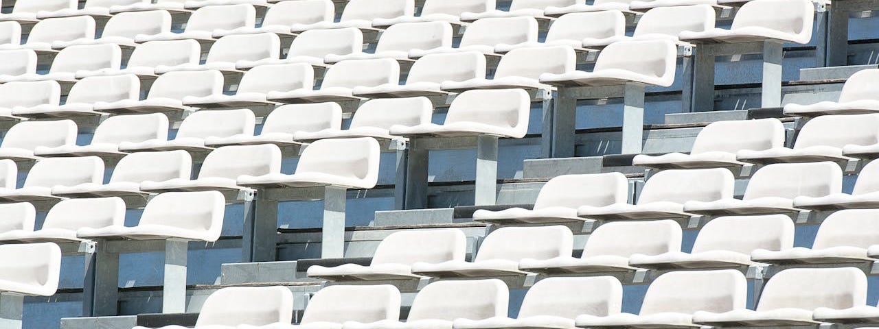 One red seat sticks out in a stadium full of white seats.