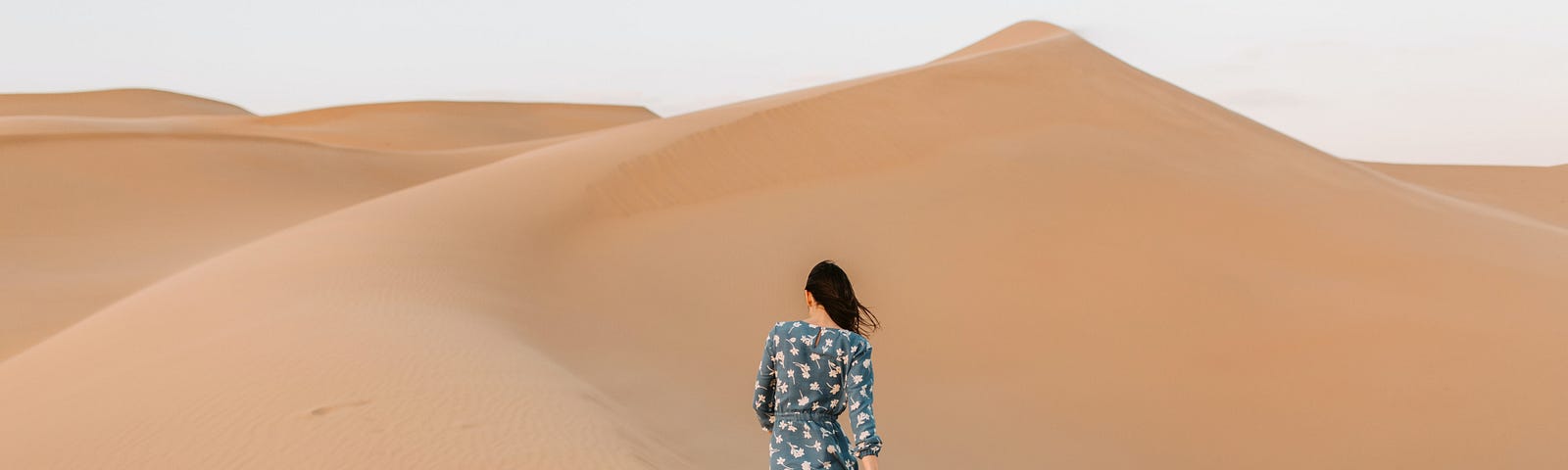 A woman in a floral dress walking in the desert