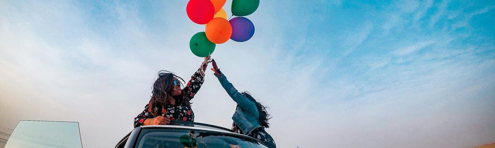 Two women release balloons into the sky on a dusty road