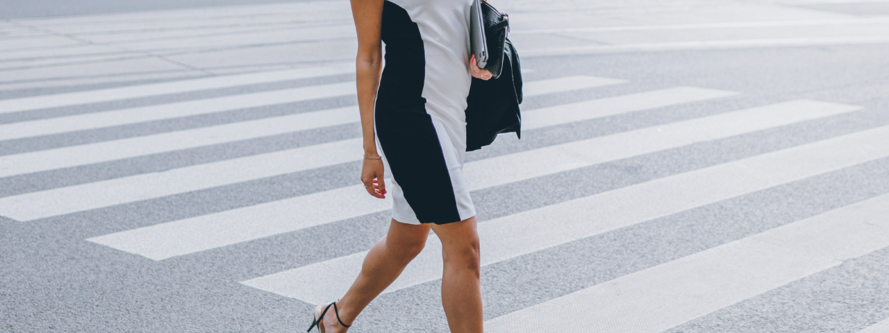 an attractive woman in a pencil dress crossing a road in the city