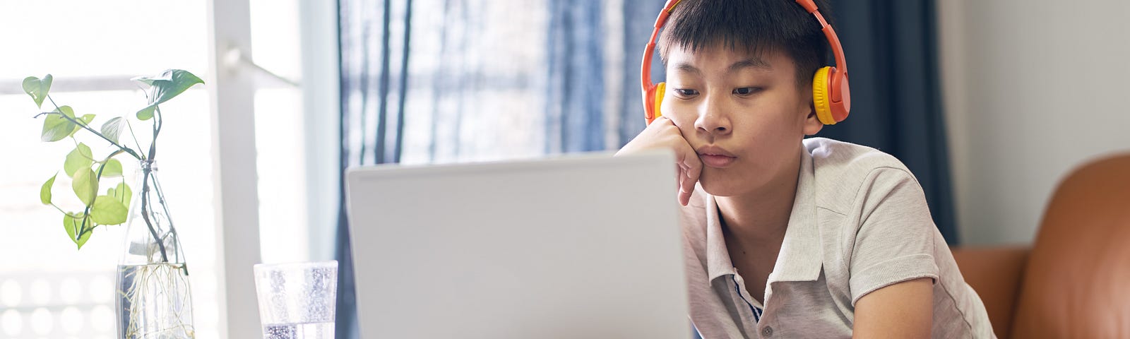 Young Asian boy using a laptop and headphones. Photo by allensima/Getty Images