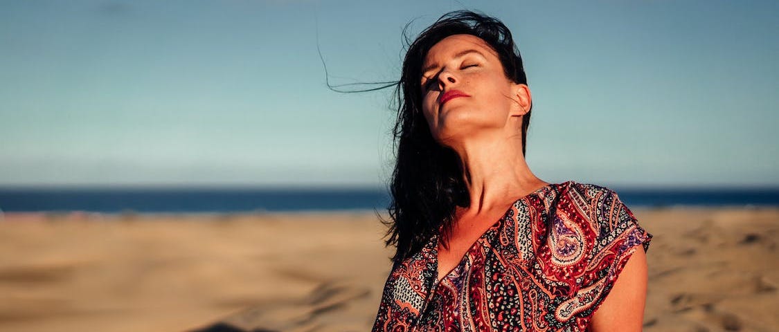 Woman wearing a beautiful dress while sunbathing at a Spanish beach. How moving to Spain changed my approach to health, fitness, and happiness