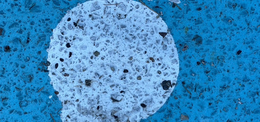 Circle painted on blue gravel sidewalk.