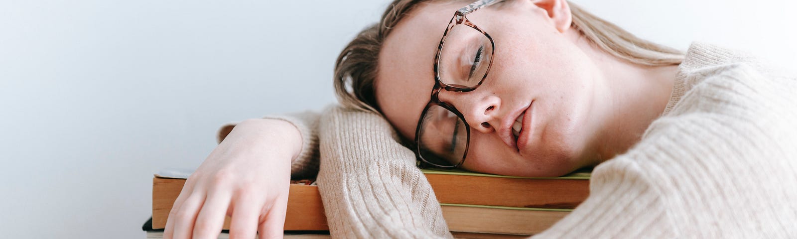 A girl sleeping, resting her head on books.