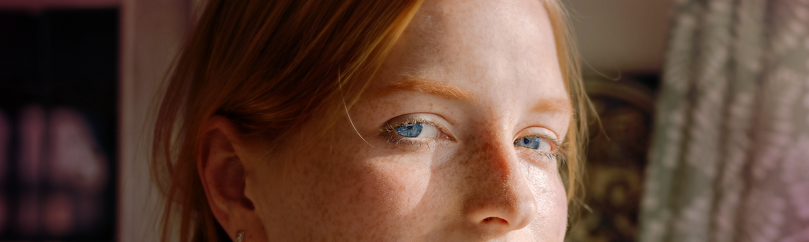 A woman with red hair and freckles looking pensive