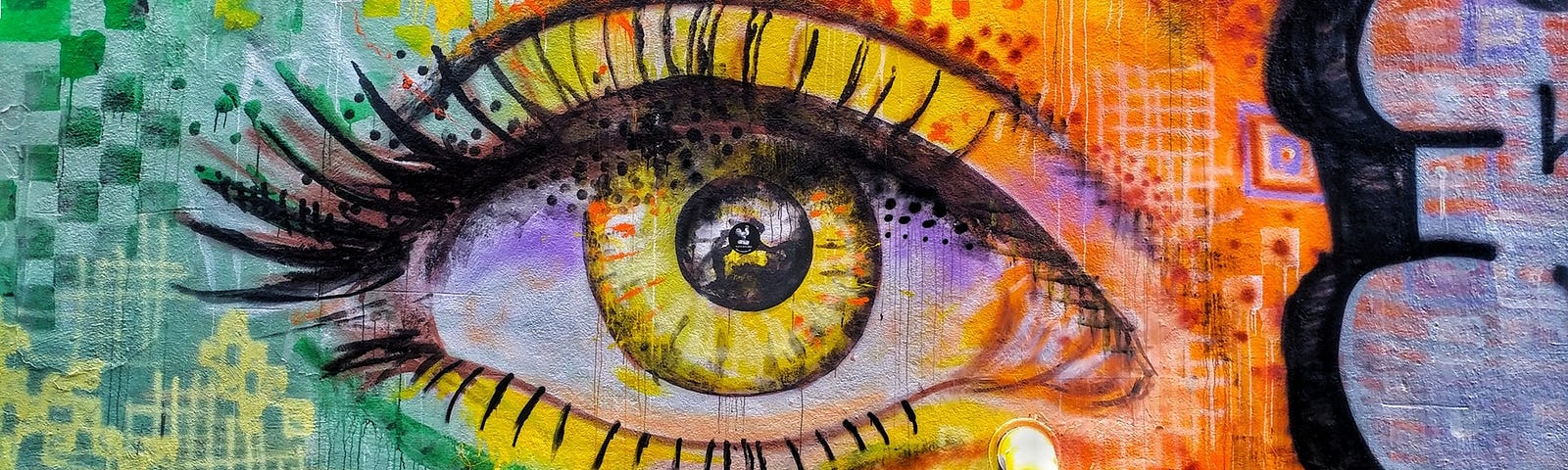 Graffiti eye on a wall in yellow, red and green, with real pipe tear duct.