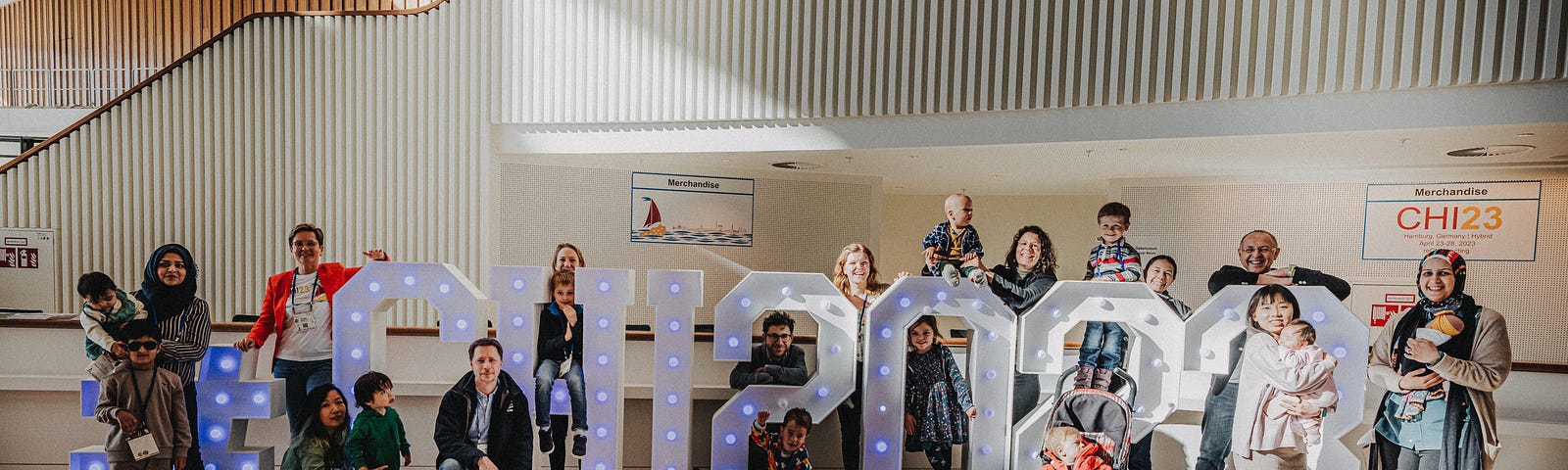 Picture of parents and kids around the CHI 2023 big letters that were in the entrance hall of the conference center.