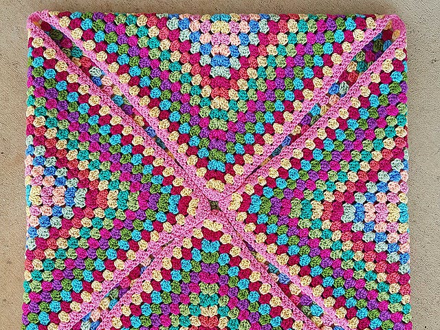 A thirty-six round granny square worked in pinks, greens, yellows, blues, and purples, with an occasional round of peach