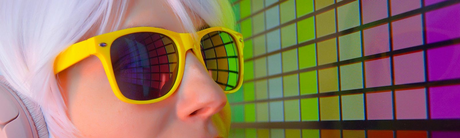 woman in yellow sunglasses facing a colorboard of lights