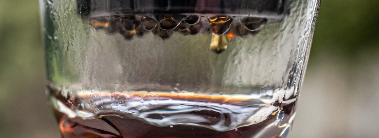 Coffee dripping from the base of the Delter into a clear glass.