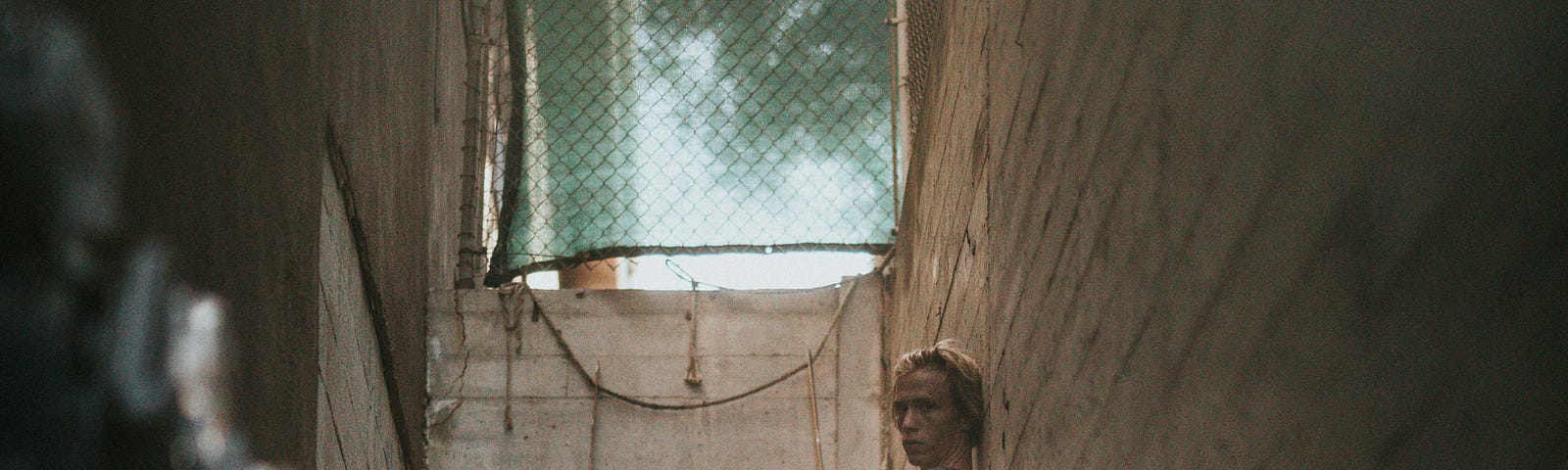 A man seemingly tired or disappointed, sitting in an alley