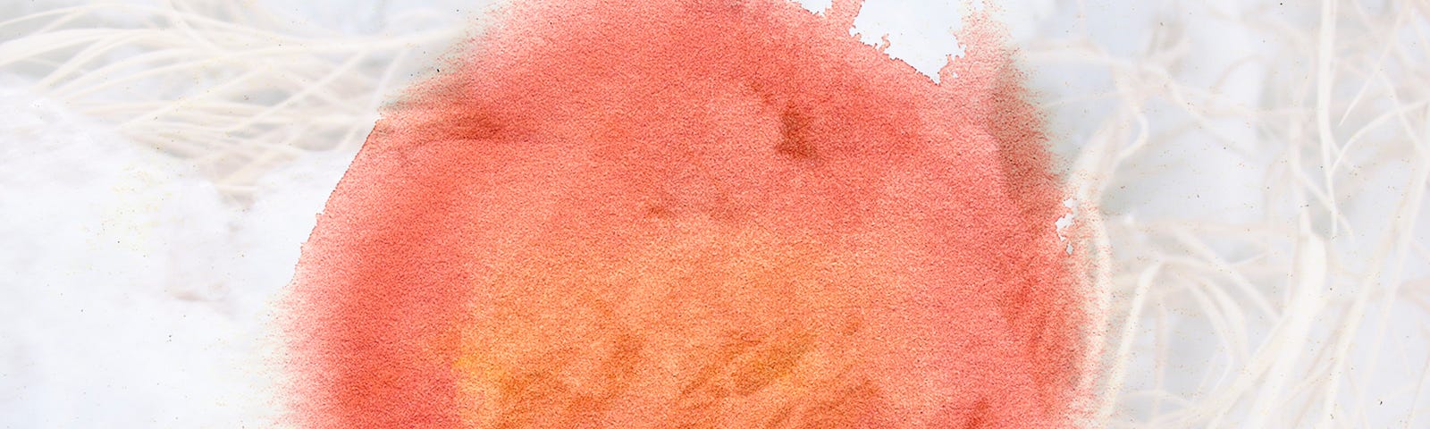 abstract art featuring a large orange circle of watercolor paint overlaid on snow covered grasses