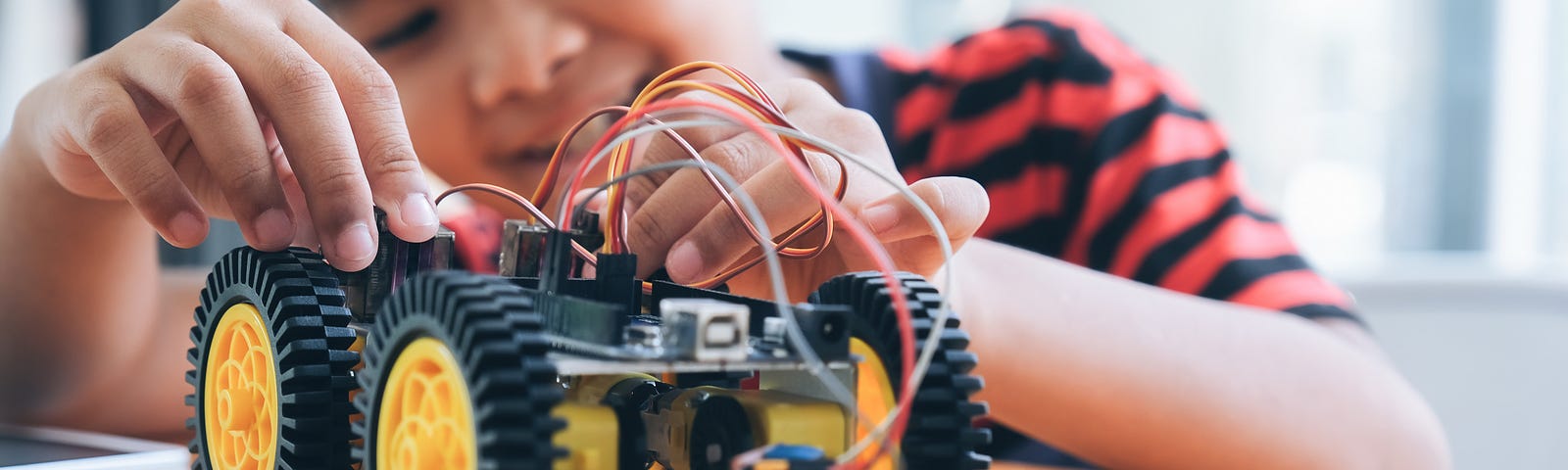 Concentrated boy creating robot at lab