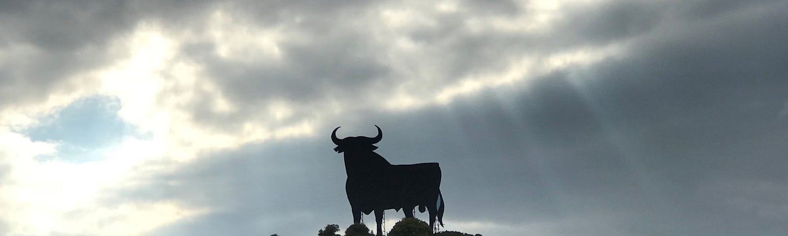 Sillouette of a metal giant bull on a hill.