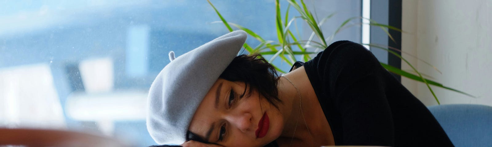 A sad-looking woman in a black long-sleeve shirt lying on a white wooden table