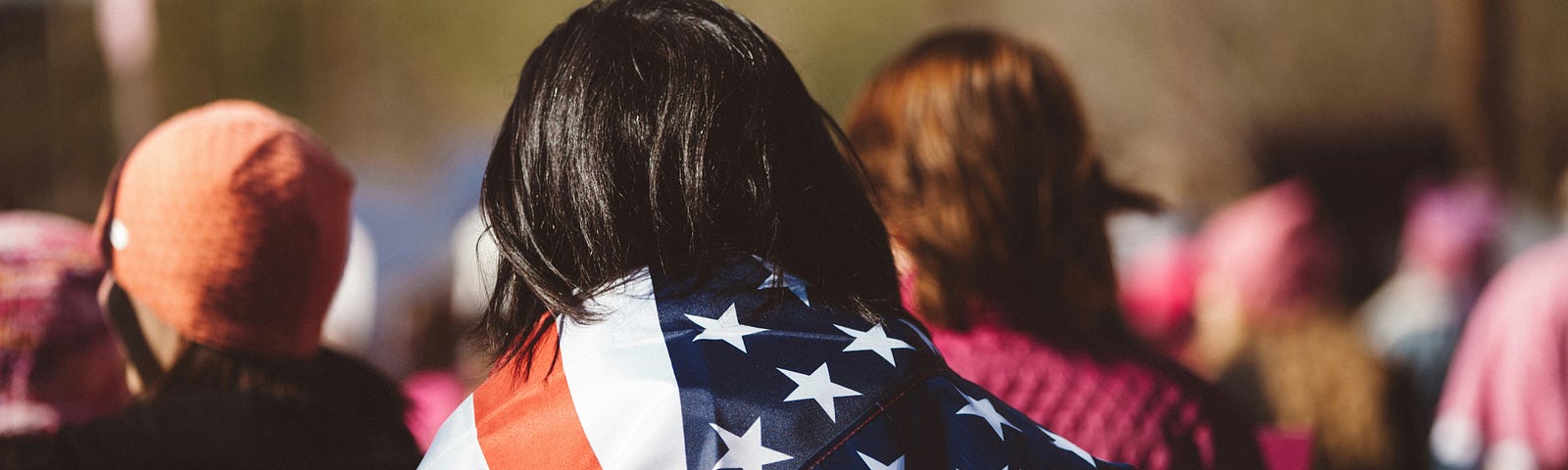 An American flag draping the shoulders of a person in a crowd.