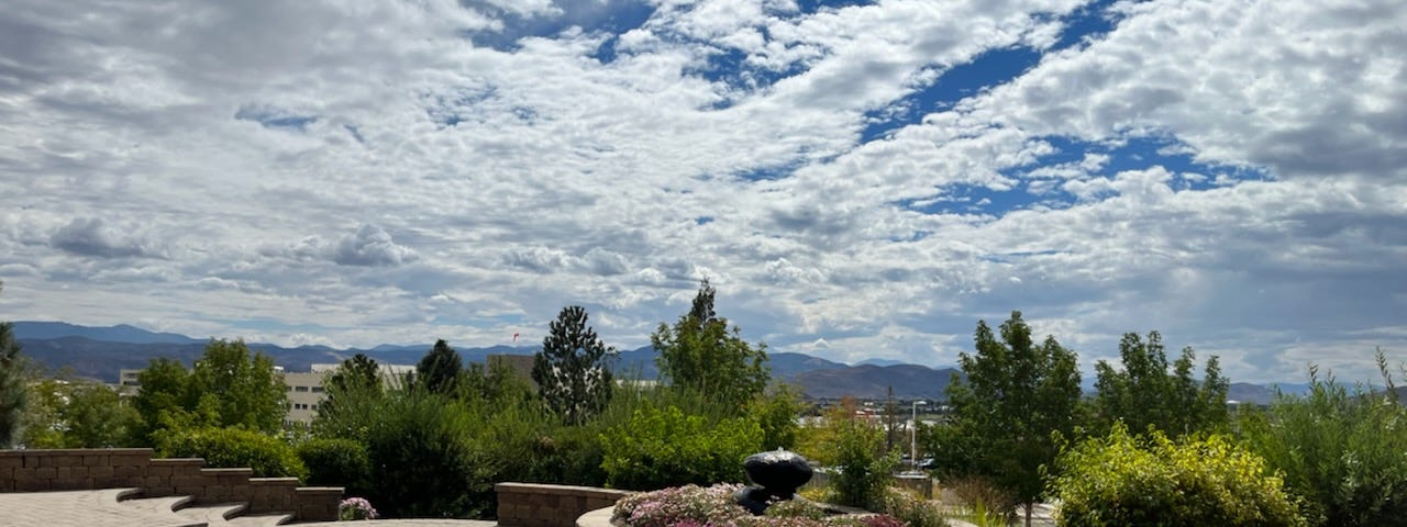 A landscaped fountain with trees, mountains, and a cloudy sky.