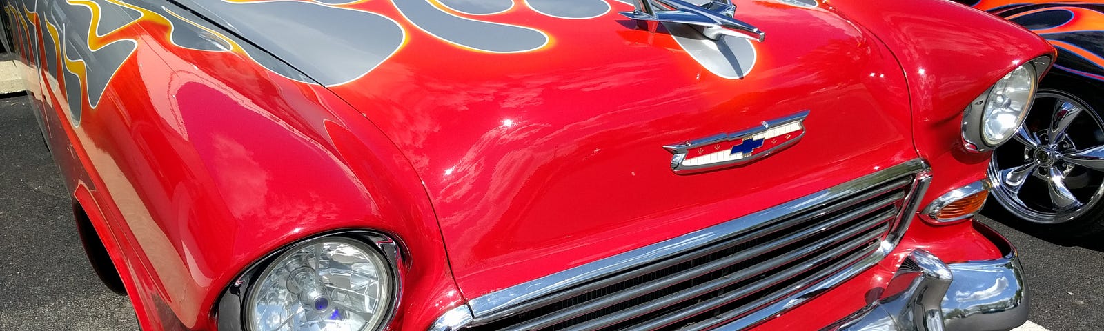 This shows an old hotrod red car with gray flames on the hood.