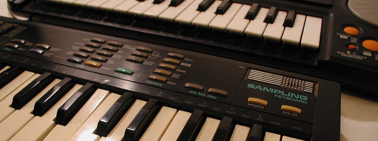 Photo of vintage mini-keyboards, forefronting the Casio SK-1 sampling keyboard of the 1980s